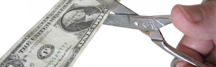 scissors cutting through a dollar bill