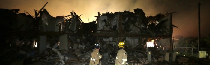 firemen searching through wreckage after plant explosion